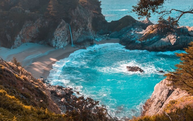 secluded bay surrounded by rocks with waves crashing